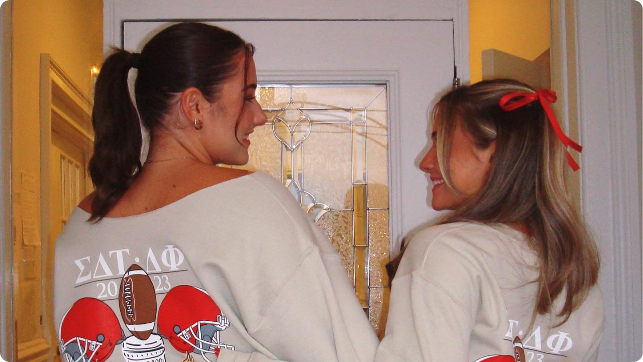 Sigma Delta Tau girls from Rutgers, The State University of New Jersey wearing custom Homecoming merch in front of a door