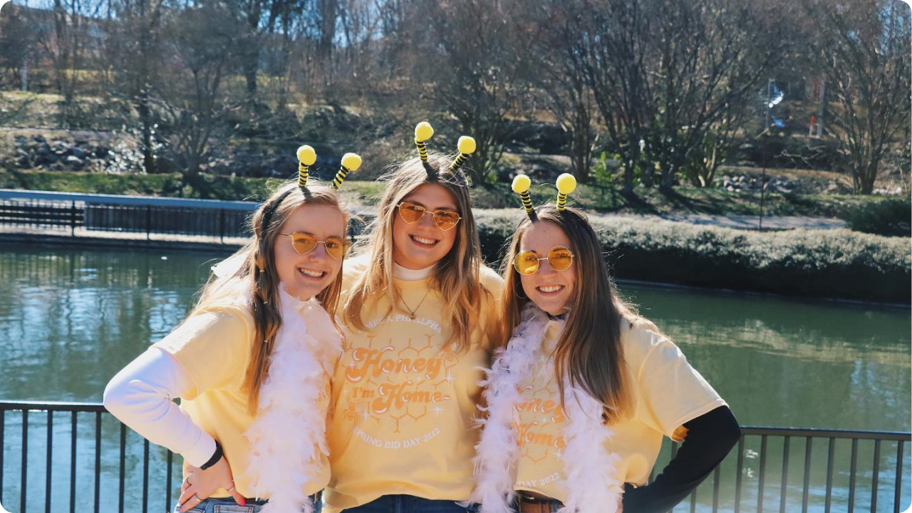 Omega Phi Alpha sorority girls wearing bee-themed Bid Day 2022 merch