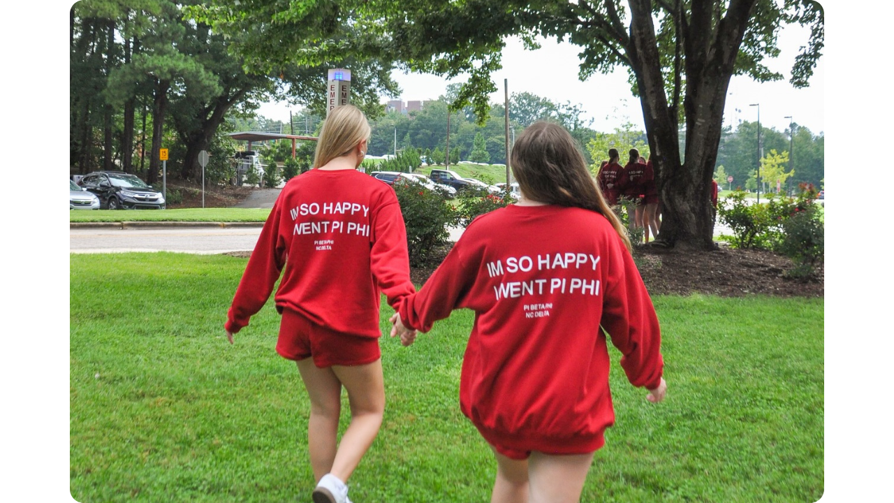 Two girls from Pi Beta Phi wearing matching red sweat sets made by Fresh Prints