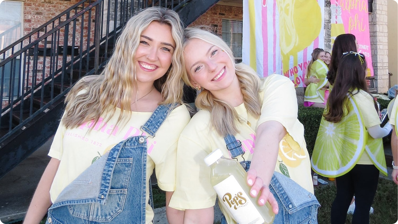 Two sorority girls wearing Alpha Phi merch and denim overalls