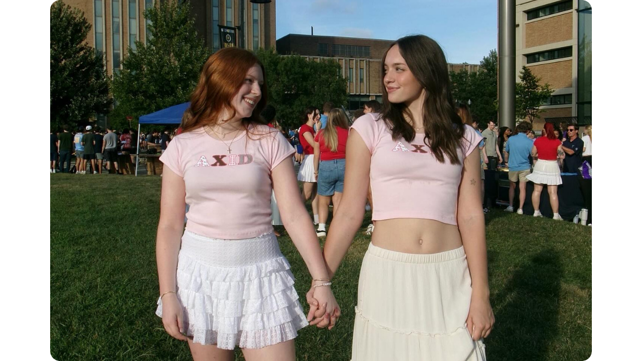 Two Alpha Xi Delta members wearing matching pink baby tees by Fresh Prints